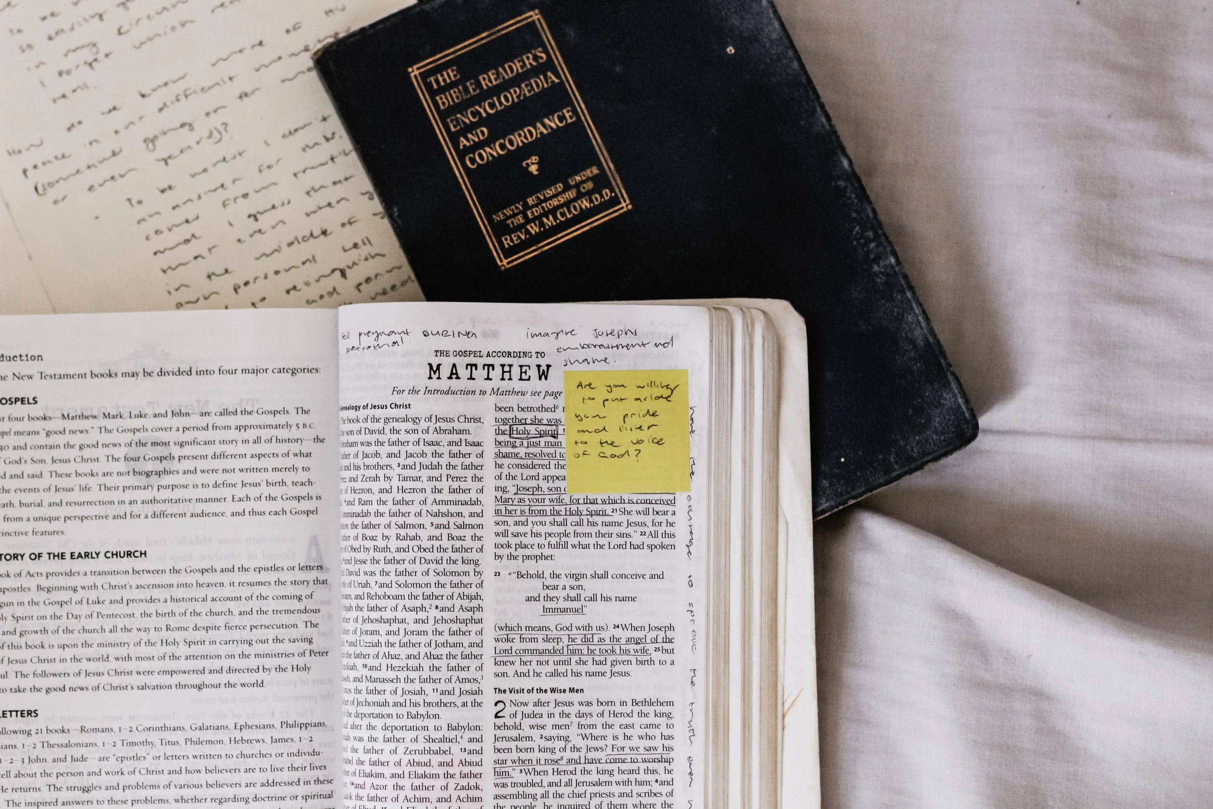 A Bible open to Matthew with handwritten study notes and a reference book